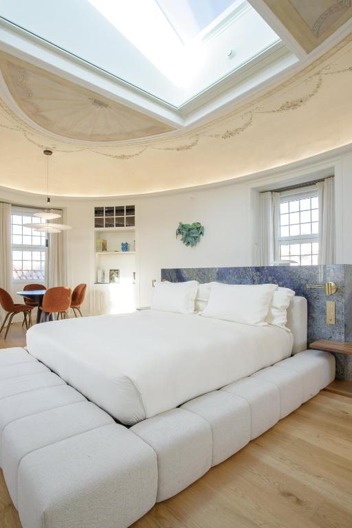 A large bed sits beneath a dramatic skylight in a bright, curved-ceiling guest room.