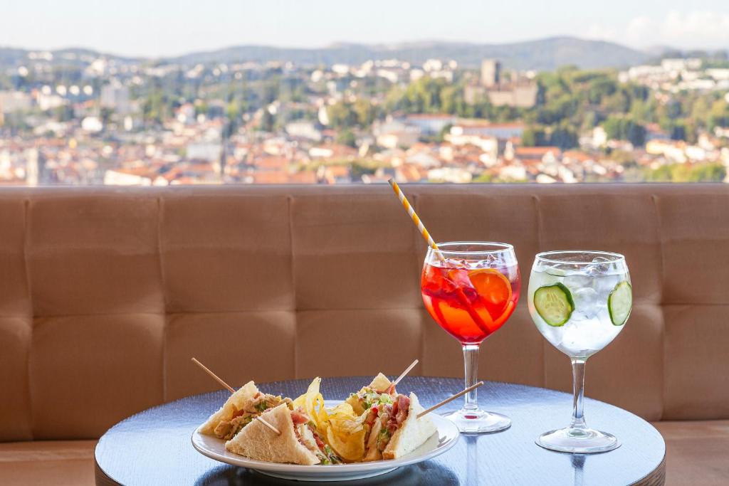 a table with a plate of food and a drink at Hotel Fundador in Guimarães