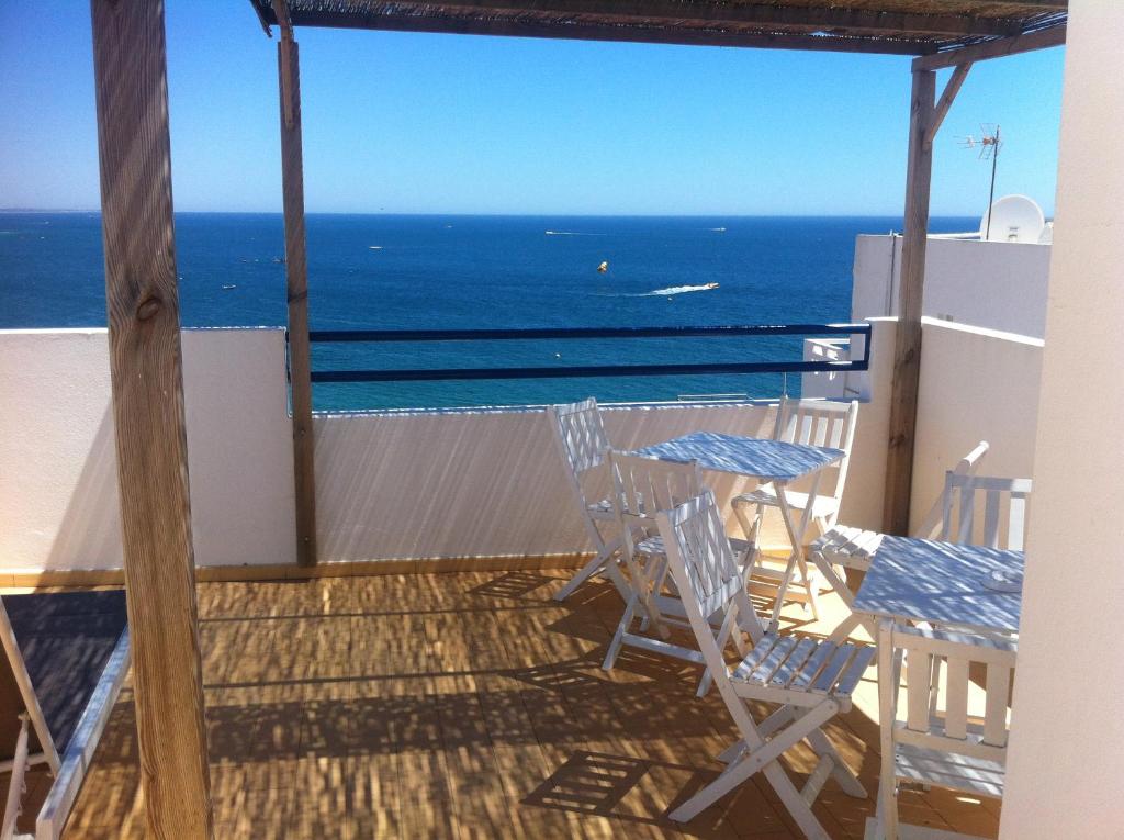uma varanda com uma mesa e cadeiras e o oceano em Apartamentos Rossio Mar em Albufeira