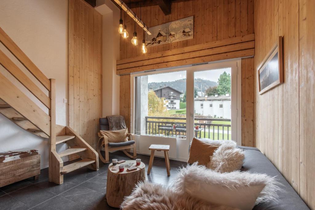 a living room with a bed and a large window at Les Chaumes - T3 moderne piscine in Cordon