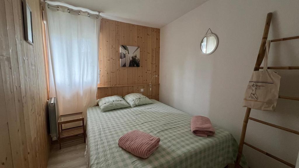 een kleine slaapkamer met een bed en een klok aan de muur bij Joli duplex 5 pers avec piscine - Cap Ferret in Lège-Cap-Ferret