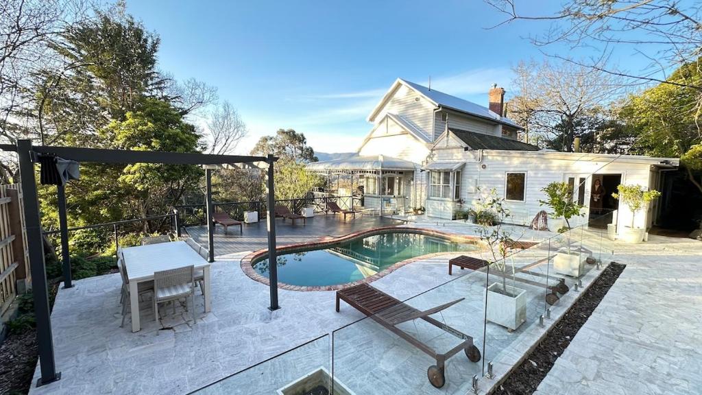 Un patio trasero con piscina y una casa. en Healesville Country House, en Healesville