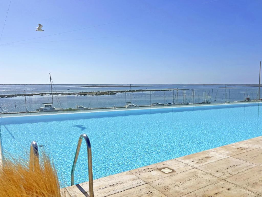 a large swimming pool with a view of the ocean at Lady Delmar Marina Olhao By Junto ao Mar in Olhão
