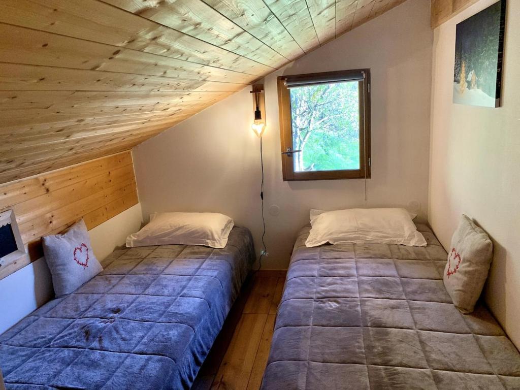 zwei Betten in einem kleinen Zimmer mit Fenster in der Unterkunft Chalet individuel en montagne in La Forclaz