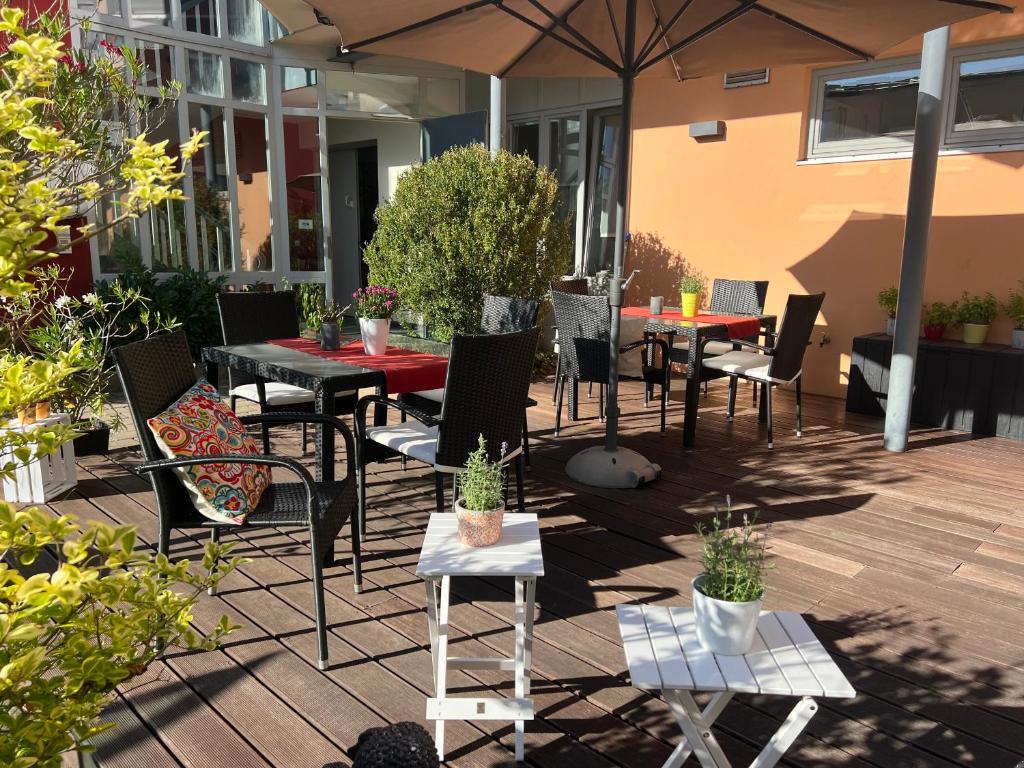 a patio with tables and chairs and an umbrella at Matchpoint Hotel in Altdorf bei Nuernberg