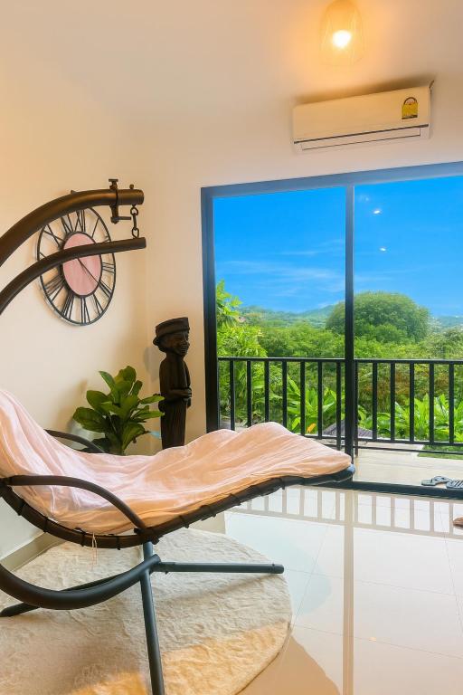 a room with a chair and a balcony with a view at Chaota Modern House in Ban Ao Makham