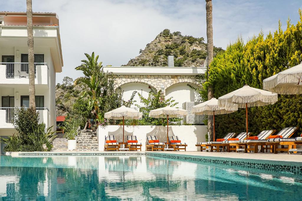 a swimming pool with chairs and umbrellas next to a building at Kassandra Boutique Hotel in Oludeniz