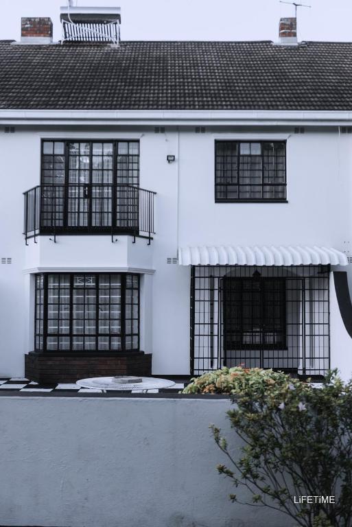 a white house with black windows and a roof at The Place in Umtali
