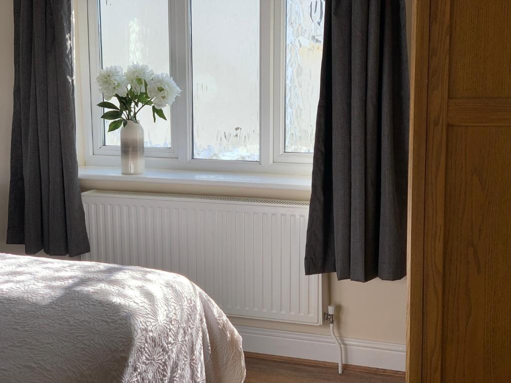 une chambre avec un vase de fleurs blanches à la fenêtre dans l'établissement Oxwich View Cottage, à Swansea