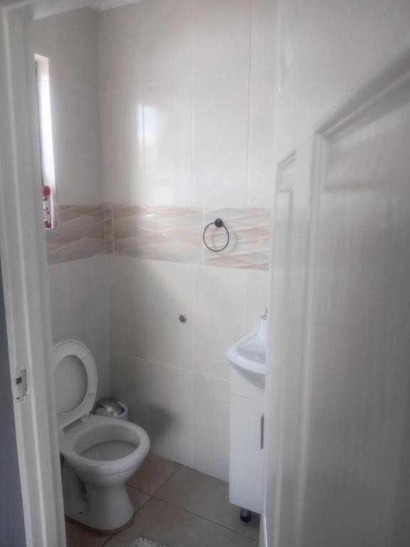 a white bathroom with a toilet and a sink at Abecor Hotel in Welkom