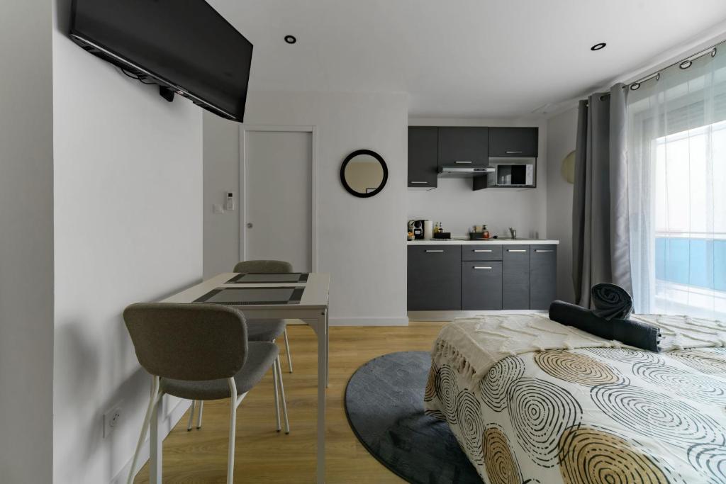 a bedroom with a bed and a desk and a kitchen at Résidence Louis B - Appartements design et climatisés in Vichy