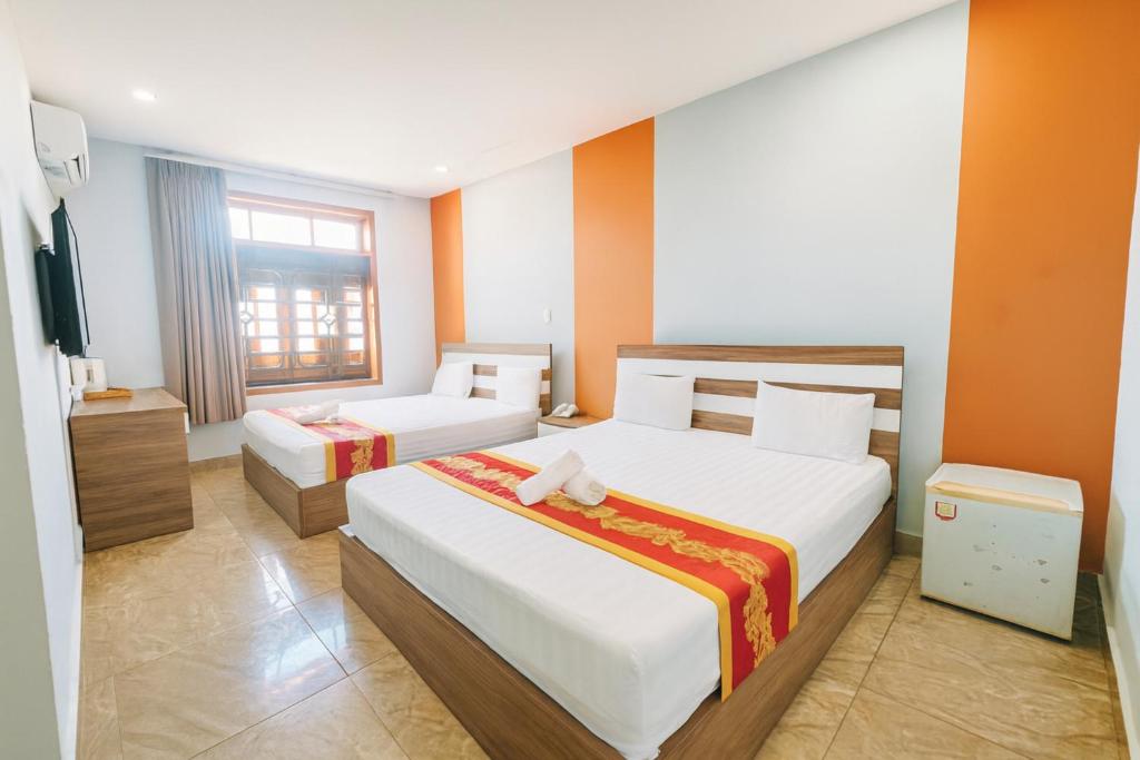 a hotel room with two beds and a television at Đức Trâm Hotel Hồ Chí Minh in Ho Chi Minh City