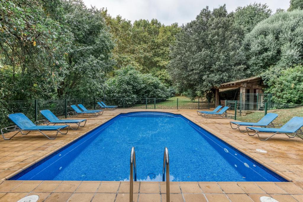 a swimming pool with blue lounge chairs and trees at Can Tapis in Santa María de Camós