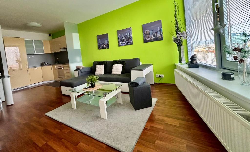 a living room with a black couch and a green wall at Three towers with parking in Bratislava