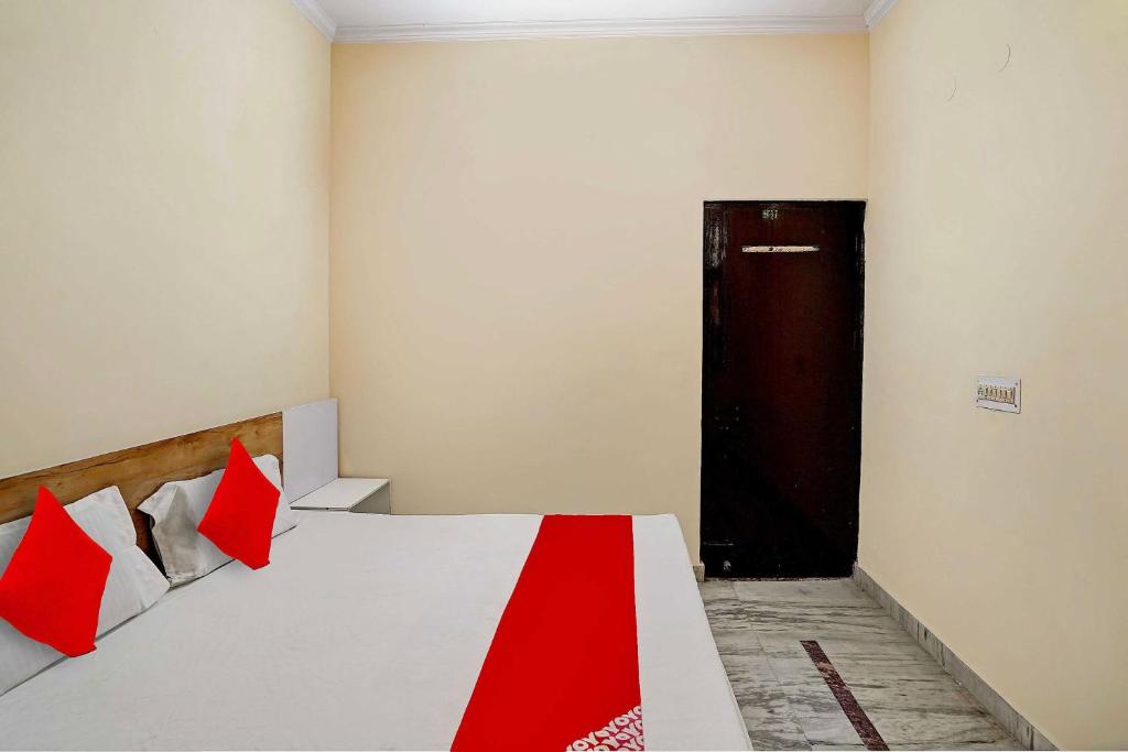 a bedroom with a bed with red pillows and a door at Hotel O The Pacific Hotel Parade Ground in Ghaziabad