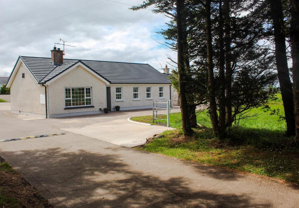 a small white house with a driveway at Creggan Deveskey Homestead in Carrickmore