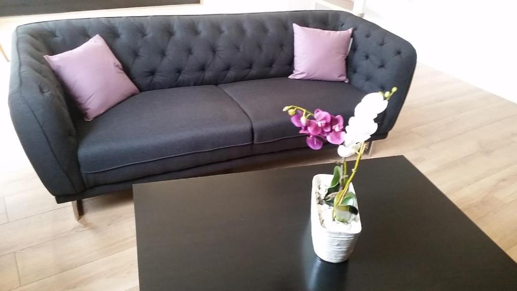 eine Couch mit lila Kissen und eine Vase mit Blumen auf einem Tisch in der Unterkunft Maison de charme Saint Valery sur Somme Baie de Somme in Arrest