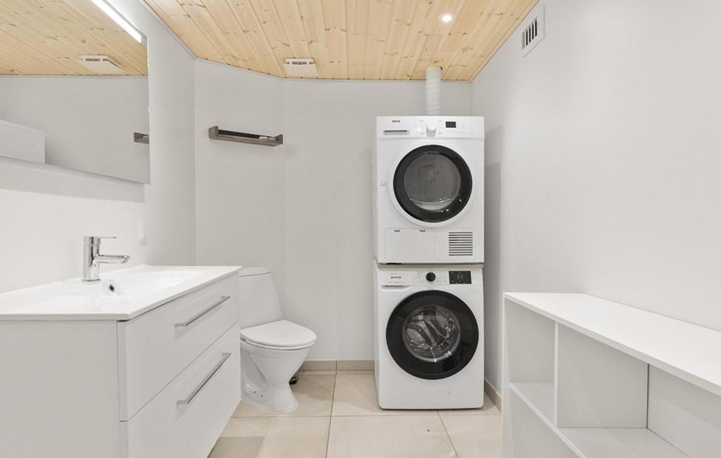 Un baño blanco con lavadora y lavadora. en Cozy Home In Løgstør With Sauna, en Trend