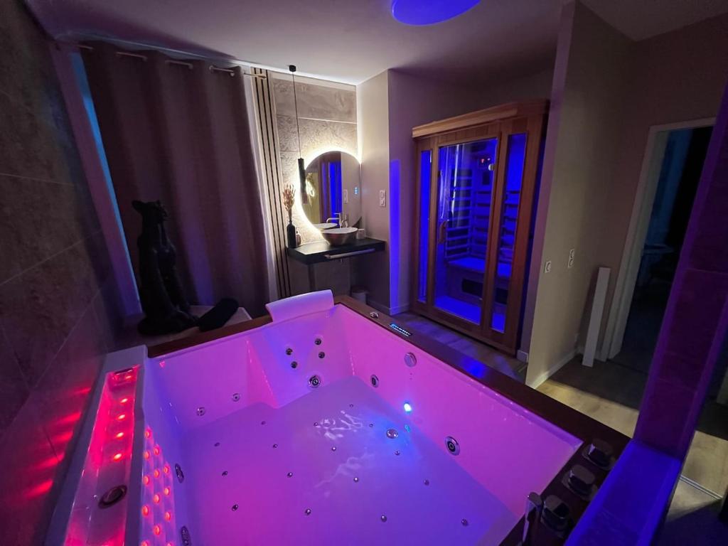 a large tub with purple lighting in a room at Suite KalypsÔ, romantisme, balnéo et sauna privé in Quimperlé
