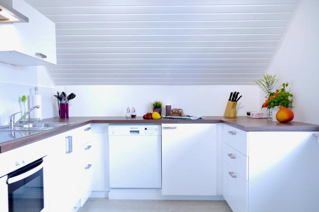 a kitchen with white cabinets and a vaulted ceiling at Ferien- Monteurwohnung in Zülpich in Zülpich