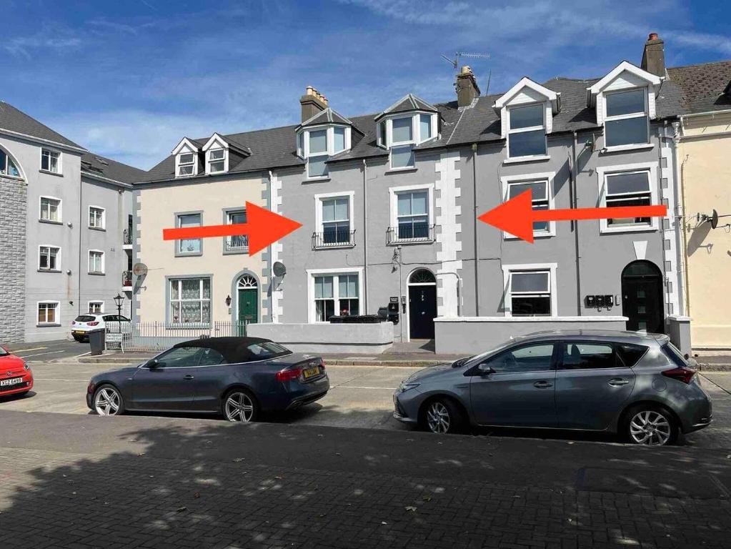 two cars parked in a parking lot in front of a building at Aurora House 2B Warrenpoint in Newry