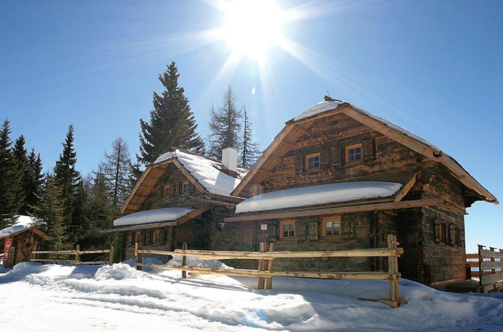 a log cabin in the snow with the sun behind it at Alpine-Lodges Matthias in Hintersauerwald