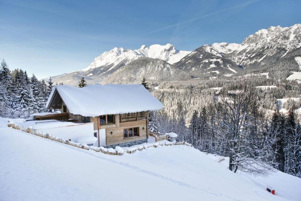 a cabin in the snow with mountains in the background at Chalet Hauserberg in Gumpenberg