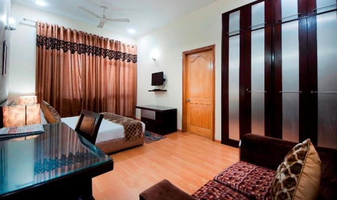 a room with a bed and a table and a couch at Imperial Apartments Huda City in Gurgaon