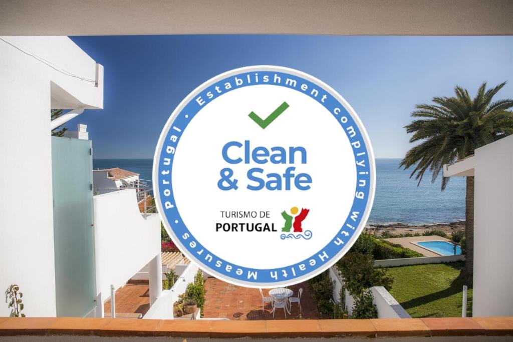 a sign for a clean and safe hotel with the ocean in the background at Calheta House in Luz in Luz