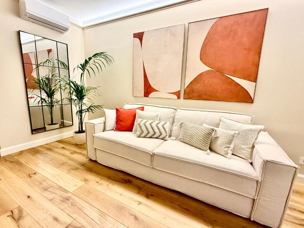 un sofá blanco en una sala de estar con pinturas en Cuneo Charme, en Cuneo