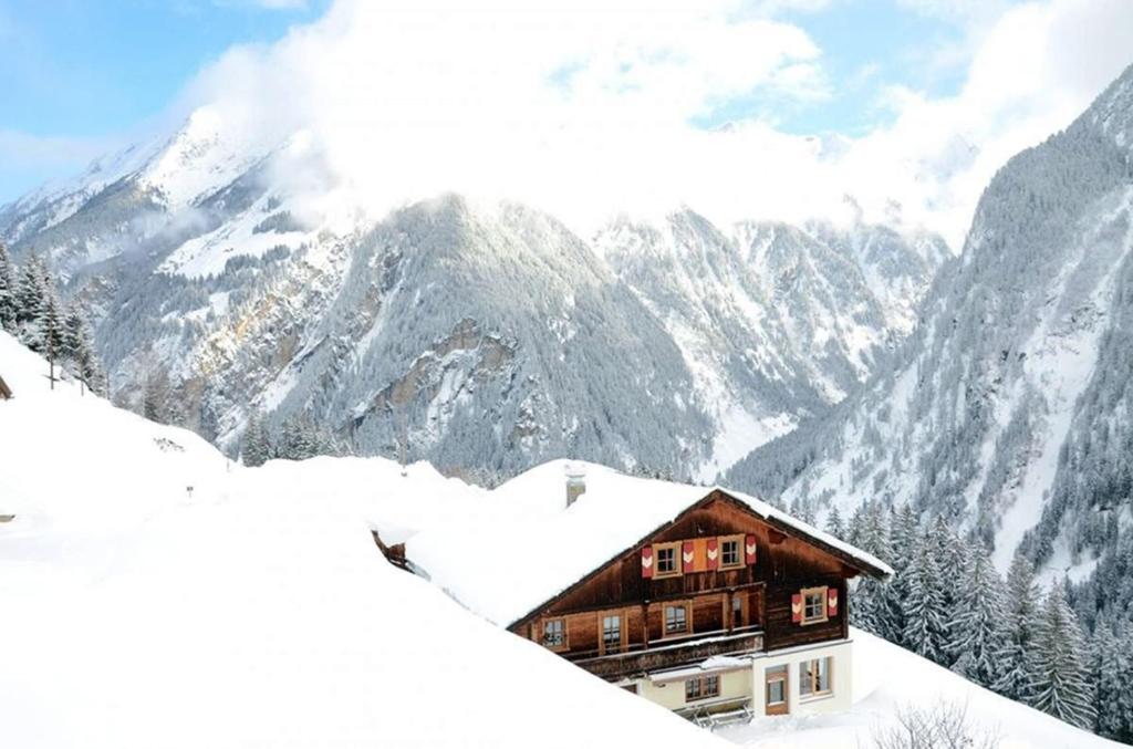 a house in the snow with mountains in the background at Alpenchalet Königreich Innerböden in Ginzling