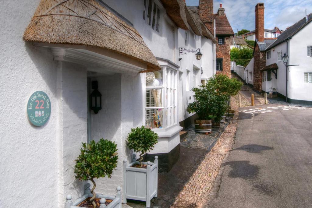 a white building with potted plants on a street at The Old Sweet Shop in Minehead