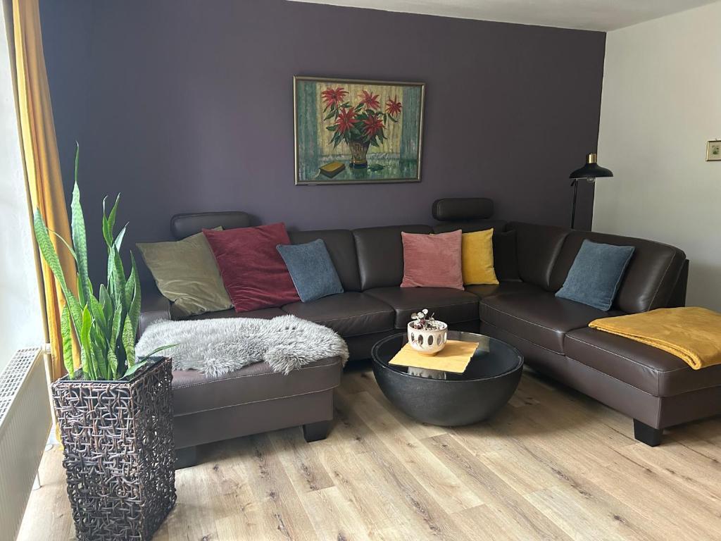 ein Wohnzimmer mit einer braunen Couch mit bunten Kissen in der Unterkunft Quartier 21 in Schortens