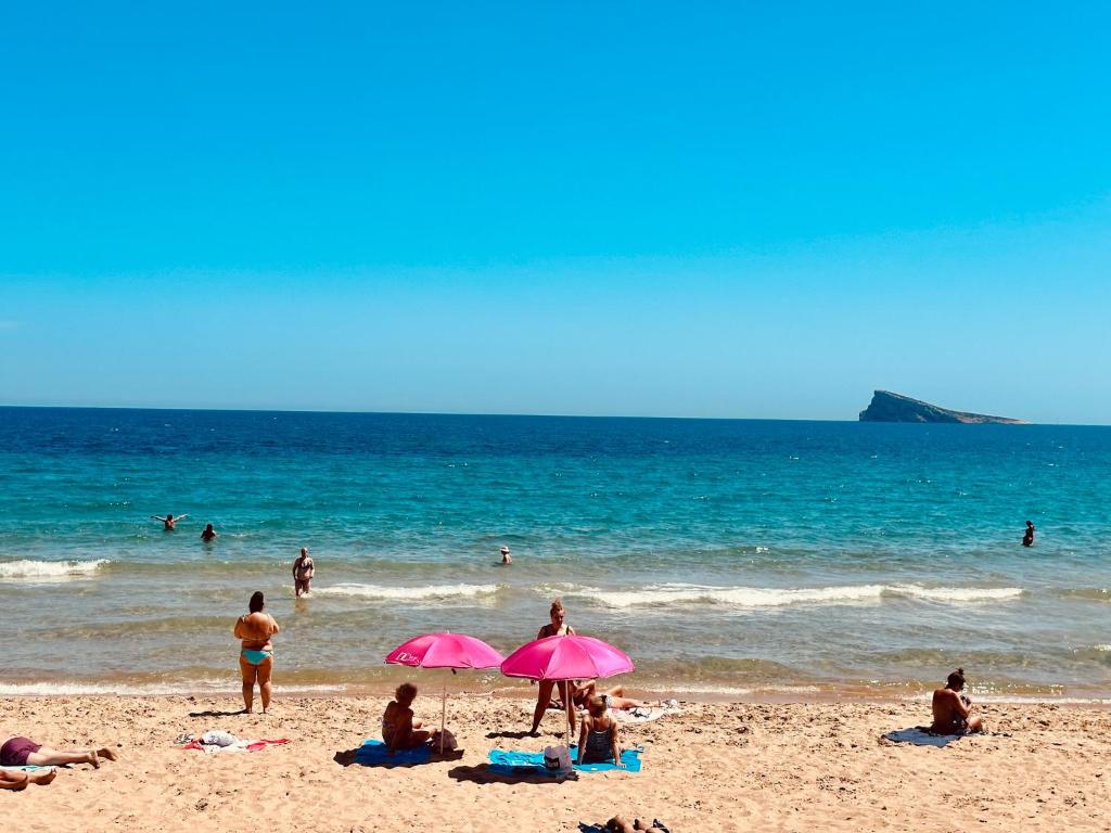 un grupo de personas en una playa con sombrillas en Carabelas 3, en Benidorm