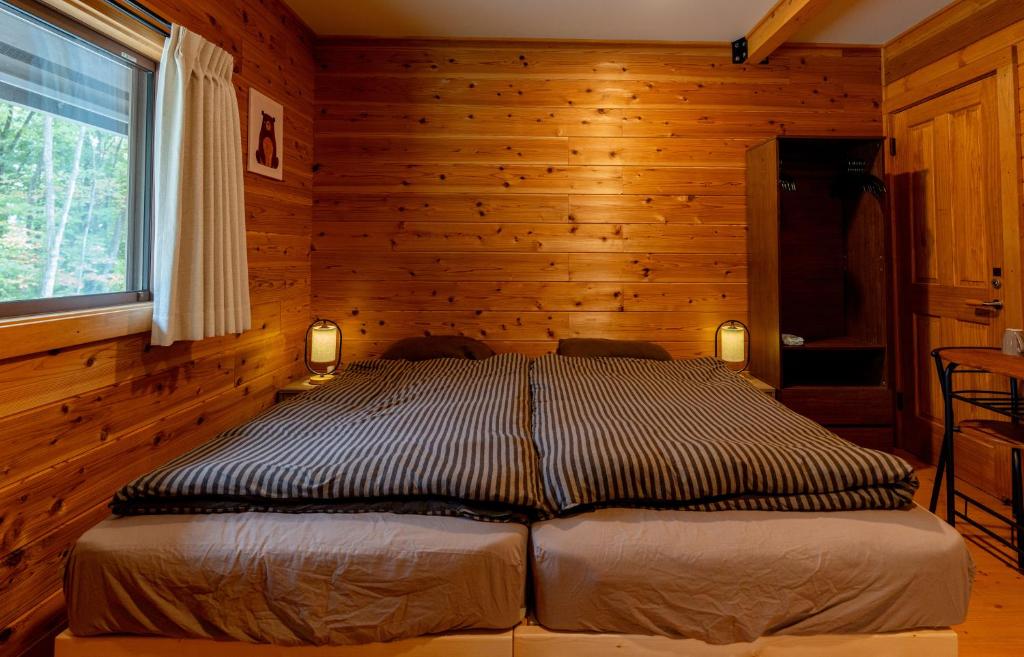 ein Schlafzimmer mit einem Bett in einer Blockhütte in der Unterkunft Azumino Bear's Inn in Azumino