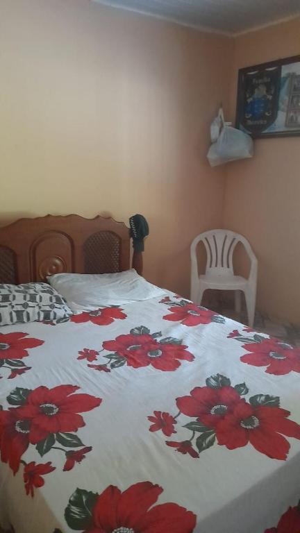 ein Schlafzimmer mit einem Bett mit roten Blumen darauf in der Unterkunft Sítio fortaleza in Salvaterra
