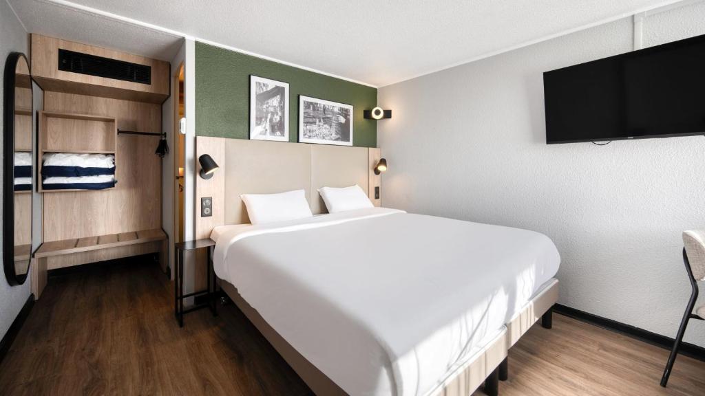 ペサックにあるCampanile NATURE - Bordeaux Sud Pessacのベッドルーム(白い大型ベッド1台、薄型テレビ付)