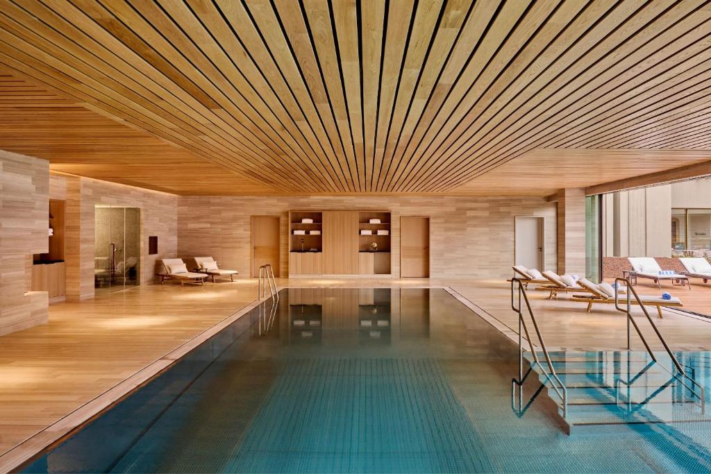 a pool with a wooden ceiling and a room with chairs at Fairmont Golden Prague in Prague