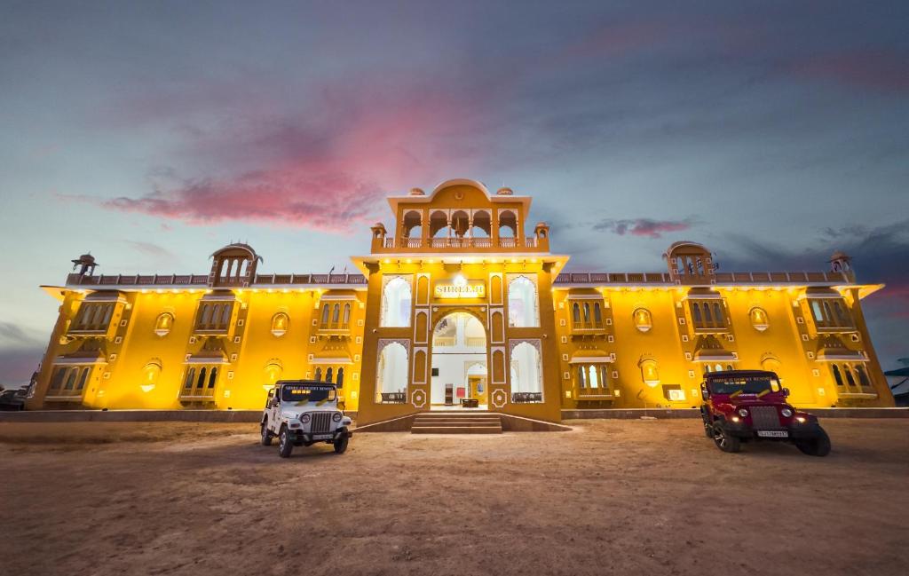 a yellow building with two vehicles parked in front of it at Shreeji Desert Resort in Sām
