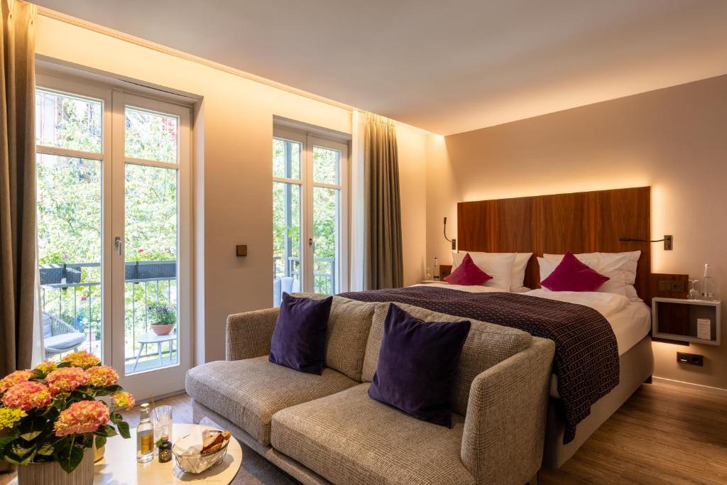 a hotel room with a bed and a couch at MAXIMILIAN MUNICH Apartments & Hotel in Munich