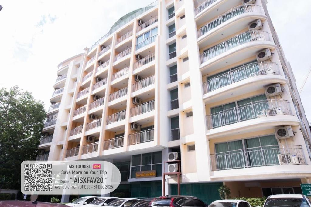 a tall white building with cars parked in front of it at Olive Hotel & Residence Bangkok Sukhumvit 101 in Bangkok