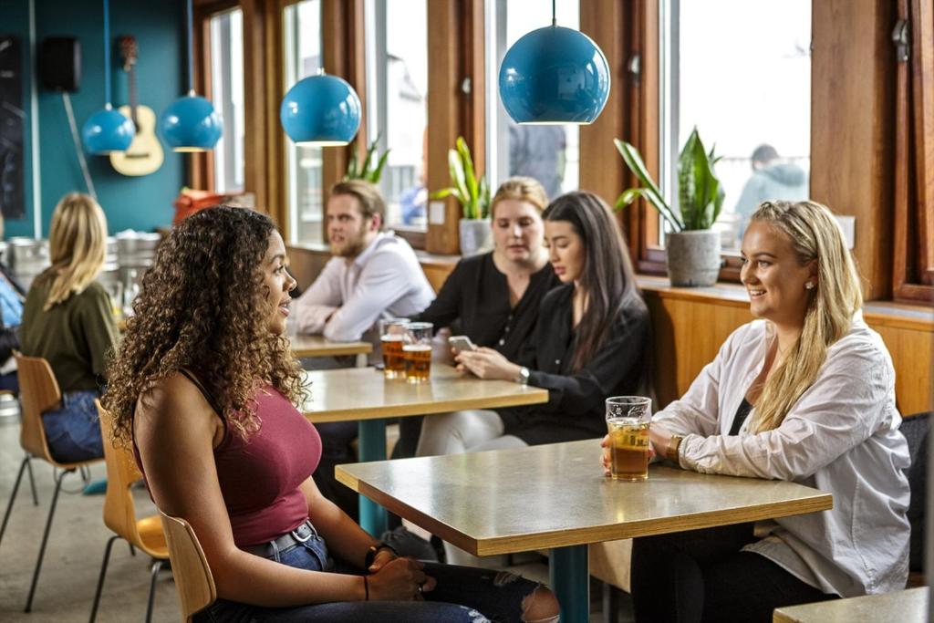 a group of people sitting at tables in a restaurant at Loft - HI Eco Hostel in Reykjavík