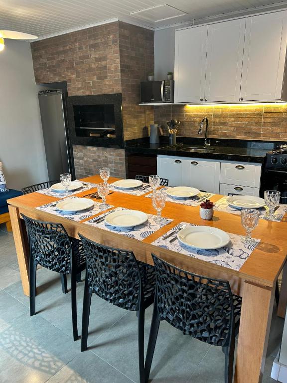 a kitchen with a table with plates and glasses on it at Solarium Riviera - Casa2 - NOVA 600m praia Riviera in Matinhos
