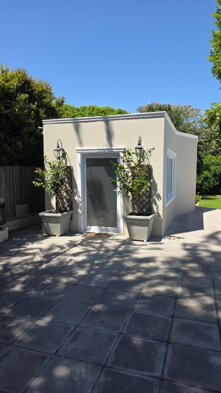 a white garage with two potted plants in it at Camellia Cottage - Pool Room in Constantia