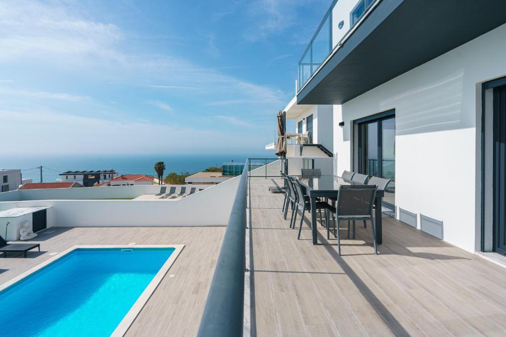 a balcony with a table and chairs next to a swimming pool at Villa Zen with sea view and private pool in Lourinhã