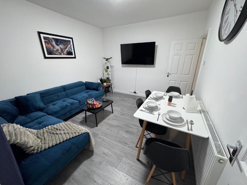 a living room with a blue couch and a table at City Escape Stylish 4 bedroom house in Nottingham in Nottingham