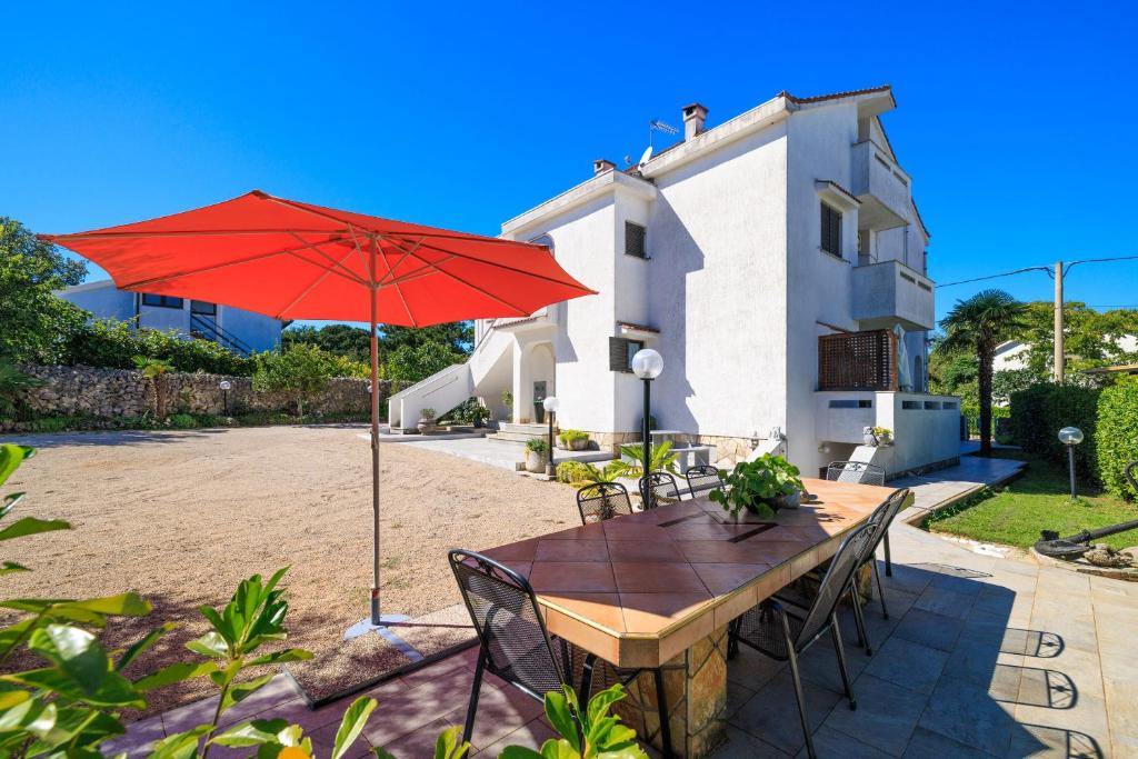 un tavolo con un ombrello rosso davanti a una casa di Apartment Dragica a Malinska