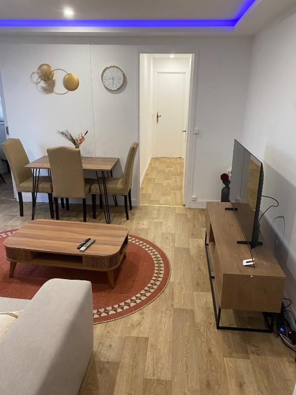ein Wohnzimmer mit einem Sofa und einem Tisch mit einem TV in der Unterkunft Appartement agréable Orleans centre-ville in Orléans