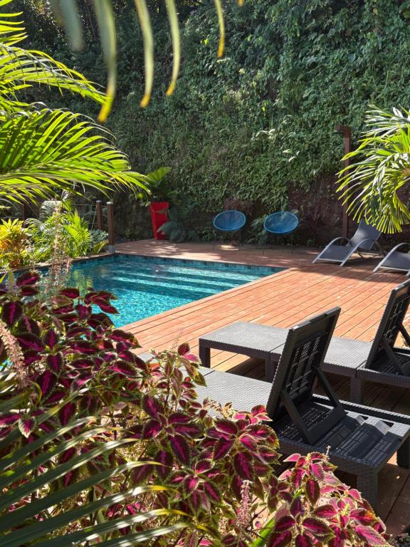 a swimming pool with a table and chairs and plants at Villa Mamalouken App Maloe in Rivière-Pilote