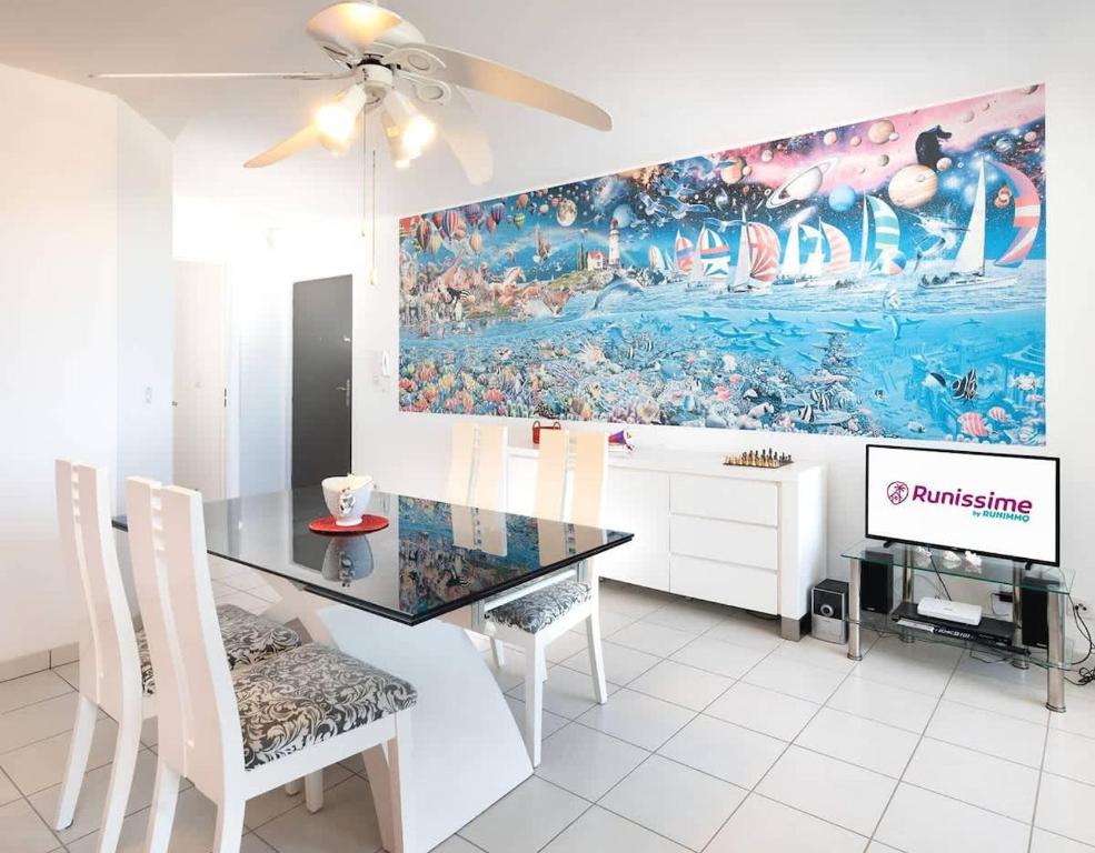 a dining room with a table and a painting on the wall at ROYCE classé 3 étoiles - Appartement 4 personnes - Vue mer - idéalement situé sur le front de mer et à 200 m du lagon de ST-PIERRE in Saint-Pierre
